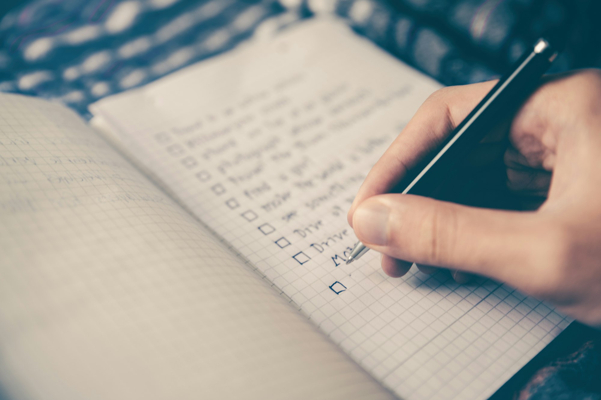 Checklist in a notebook beside a laptop